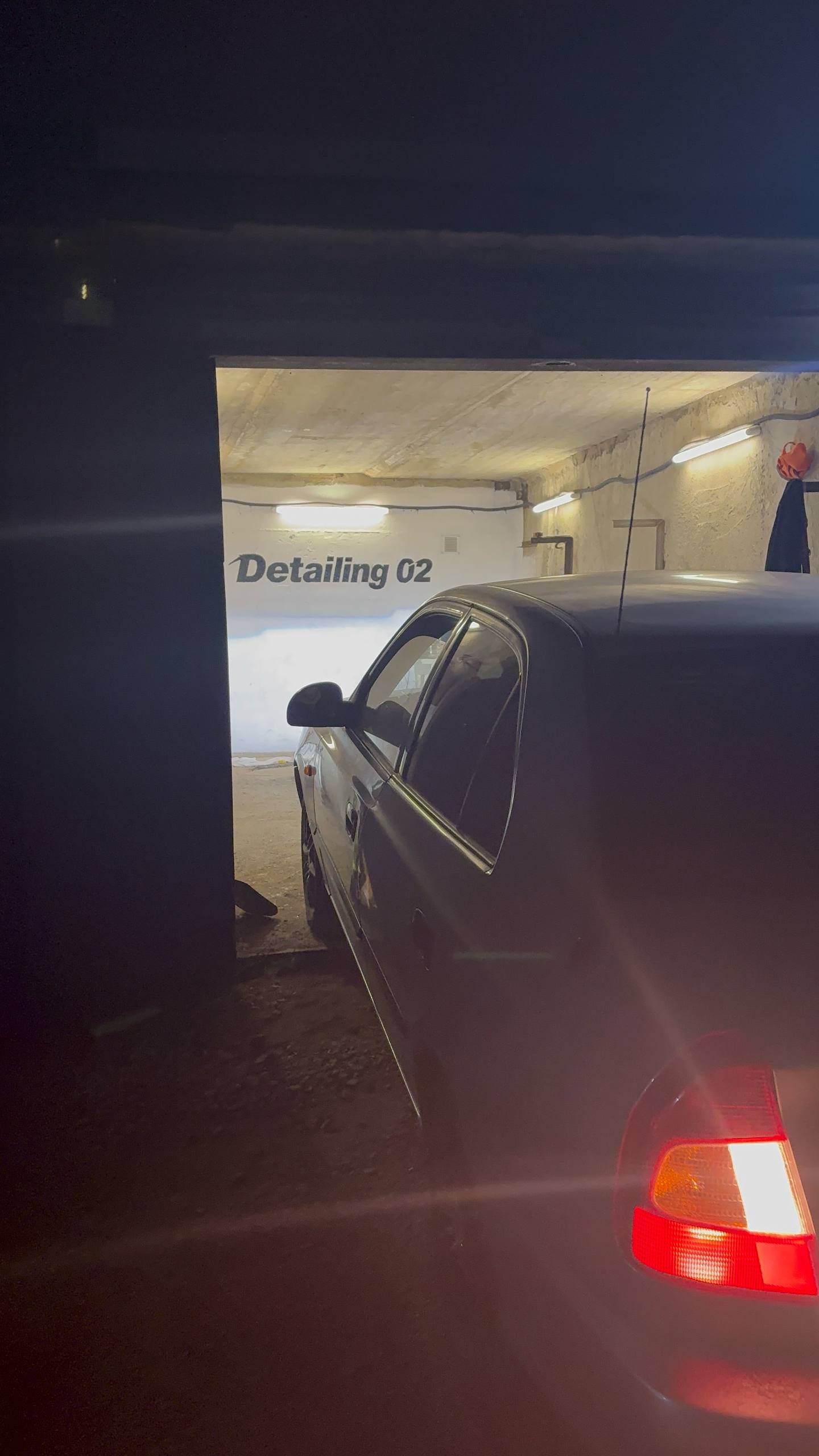 Вход в бокс Detailing 02 вечером, на стене светится логотип
